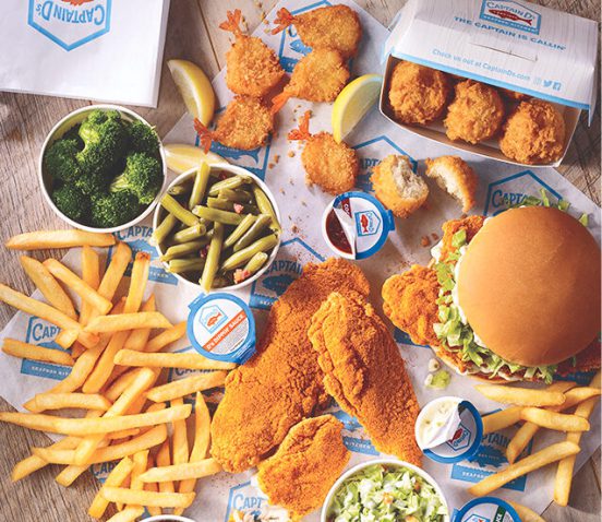 Table full of various fried seafood, fries, condiments and vegetables